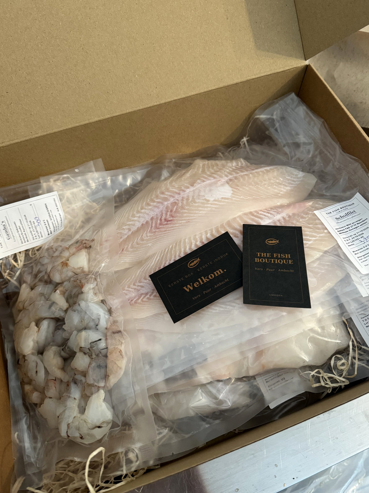 Geopende Signature Box van The Fish Boutique met verse visfilet, gamba's en welkomstkaart, vers van de afslag in IJmuiden